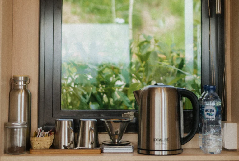 A beautifully arranged coffee corner in the cabin, complete with a kettle, cups, and coffee-making tools. The window offers a view of the surrounding greenery, adding a peaceful touch to the space.