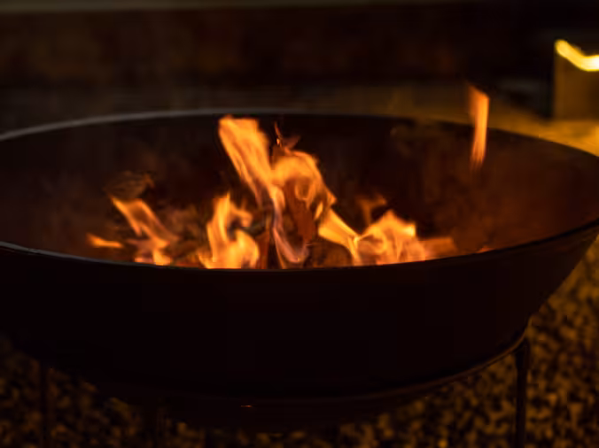 A warm bonfire flame glowing in a fire pit at Rimbun Farm, perfect for evening gatherings.