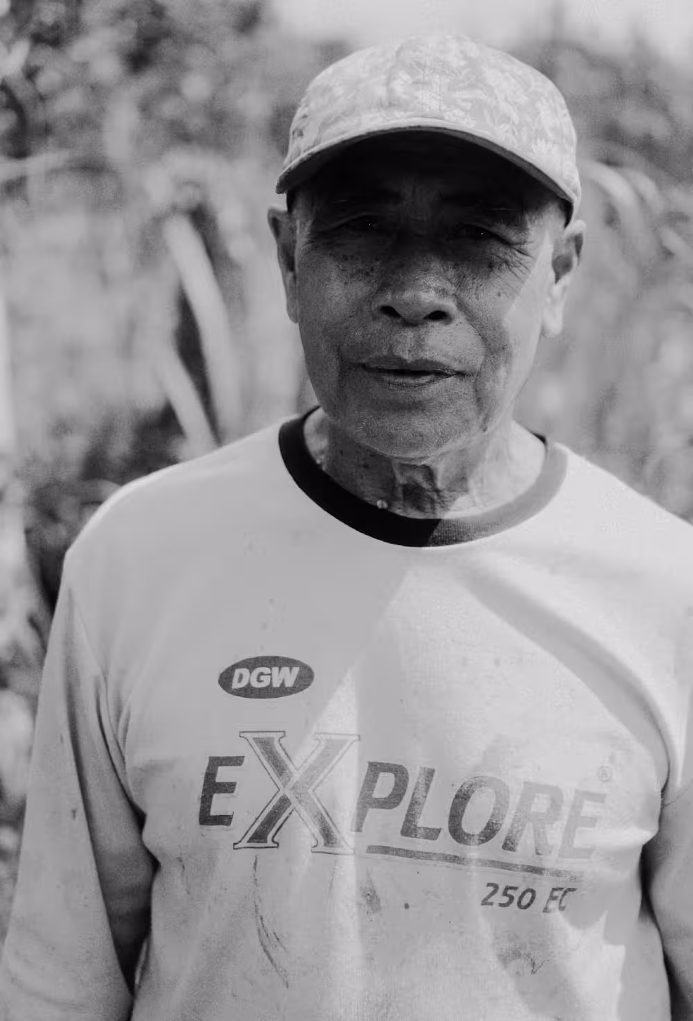 An elderly farmer at Rimbun Farm, proudly standing in the fields with a calm expression, showing the hard work of farming.
